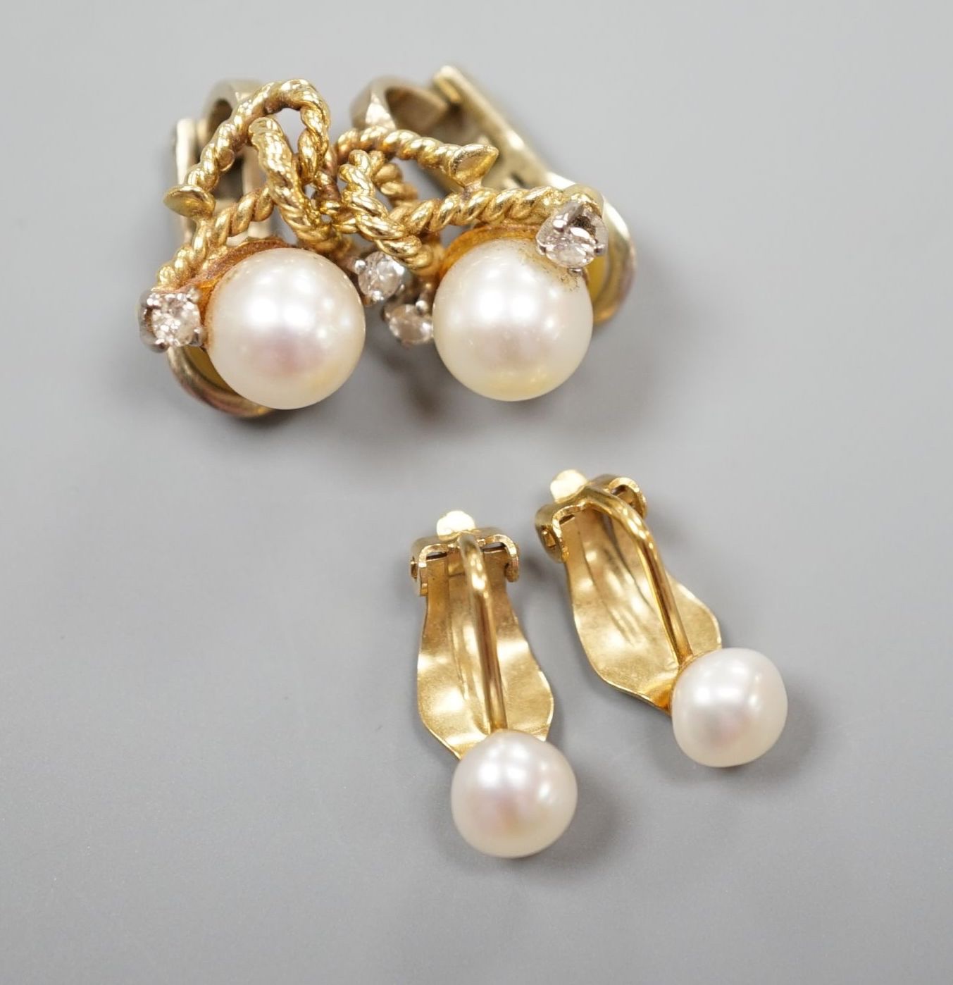 A pair of 20th century yellow metal, diamond and cultured pearl set ear clips, 18mm and a pair of yellow metal and cultured pearl set ear clips, gross 10.3 grams.